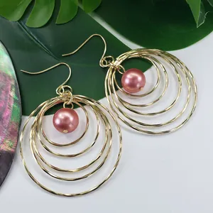 Detail of gold multi-layer hollow round earrings with pink mother of pearl beads