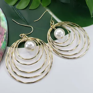 Detailed macro view of gold multi-layer circle earrings with elegant white pearl drops