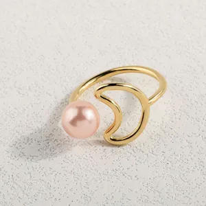 Detailaufnahme von goldenem offenem Ring mit rosa Perle und Mondsichel-Design