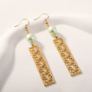 Macro shot of gold leaf-clover earrings with pale green pearl and hollowed metal bars
