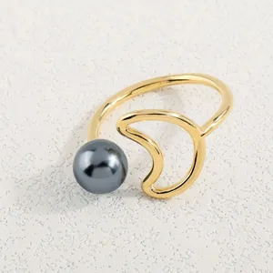 Detailaufnahme eines minimalistischen Goldrings mit grauer Perle auf Steinfläche