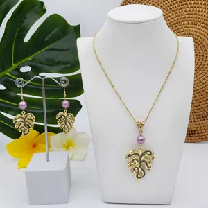 Detail of tropical monstera leaf jewelry set with gold finish and purple pearls