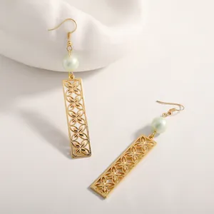 Detail of gold drop earrings featuring hollow clover pattern and pale green pearls