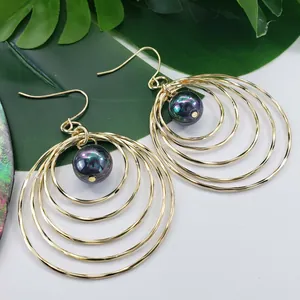 Detail of bohemian gold hollow circular drop earrings with iridescent aurora pearl bead