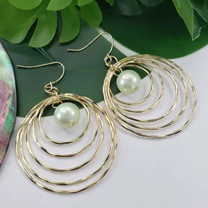 Detail of gold multi-layered circular earrings featuring a mint green pearl center