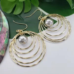 Detail of layered gold round earrings featuring grey pearl accents and a hollow design