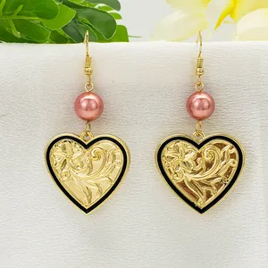 Makroaufnahme von Vintage-Herzohrringen aus Gold mit Blumenprägung und rosa Perlen