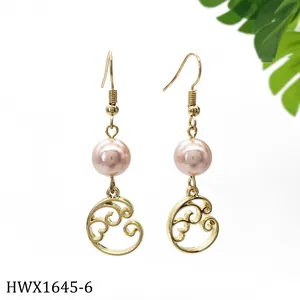 Makroaufnahme von goldenen Ohrhängern mit rosa Perlen und gewellten Anhängern