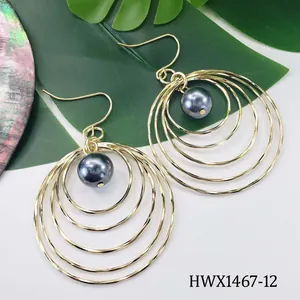 Detailed view of layered gold hoop earrings with a central grey pearl and shiny finish