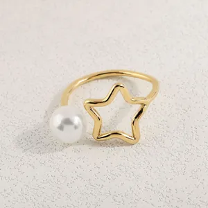 Detail eines verstellbaren Goldrings mit hohlem Stern und Perle auf Sandtextur
