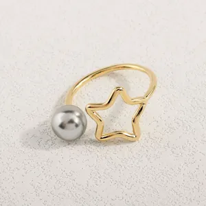 Detailansicht von goldenem Stern und grauer Perle auf einer offenen Ringschiene