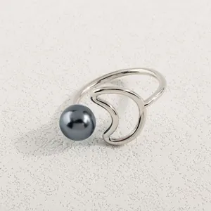Details des minimalistischen Mondrings mit grauer Perle auf beigem Hintergrund
