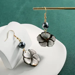 Boucles d'oreilles élégantes avec fleurs en nacre noire et crochets dorés sur support