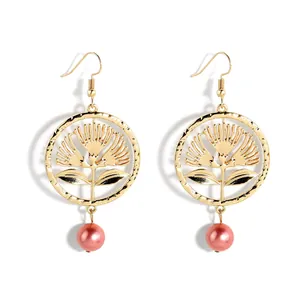 Makroaufnahme goldener Hohlring-Ohrringe mit Blumenmotiven und rosa Perlenanhängern