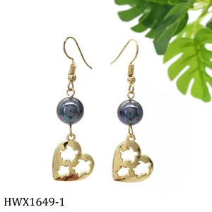 Detailansicht goldener Herz-Ohrhänger mit lila Perlen und Haken-Design auf Weiß