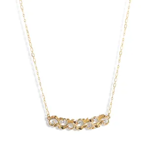 Detail van gouden wijnstok ketting met bloemhanger en schitterende zirkonia steentjes