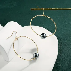 Minimalist gold hoop earrings with dark grey mother-of-pearl pearls and hammered texture