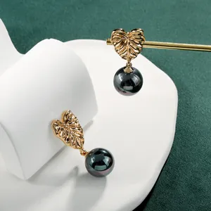 Elegante monstera blad oorbellen met gouden harttextuur en donkere iriserende parels