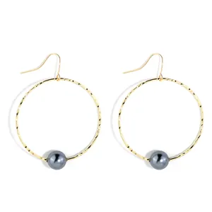 Minimalist gold hammered hoop earrings with dark grey pearl charms on white background