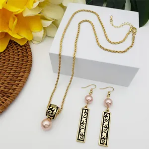 Detailed view of Polynesian style gold jewelry set with pink pearls and black scroll relief
