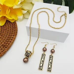 Detail of gold necklace and earrings with black Samoan totem patterns and pearls