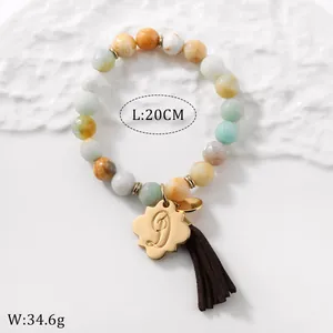 Detail of colorful stone beaded bracelet with gold flower letter D charm and brown tassel
