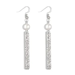 Detail of silver plated drop earrings featuring shell pearls and floral engraved bars