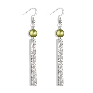 Detail of silver drop earrings featuring olive green bead and engraved vine patterns