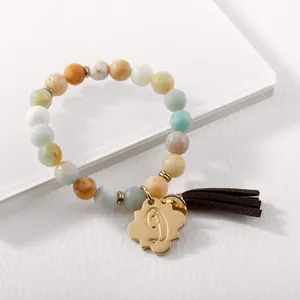 Detail of beaded bracelet with golden flower charm and letter D engraving with tassel