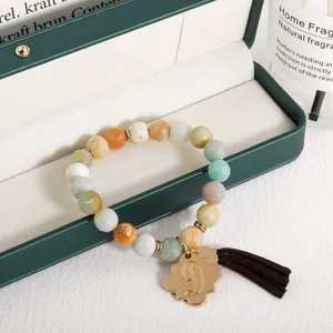 Detail of bohemian beaded bracelet with natural stones, gold D-pendant, and brown tassel