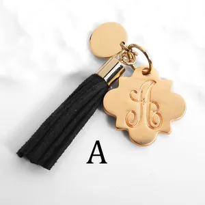 Detail of a golden letter A charm featuring a black tassel and floral metallic plate