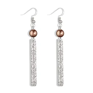 Detail of silver drop earrings with brown pearl beads and floral textured bar pendants