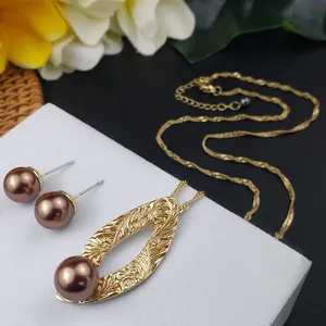 Hawaiiaanse sieradenset met gouden hangers en bruine parel oorbellen op tafel