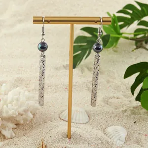 Hawaiian drop earrings with dark pearl and engraved silver bars on beach background