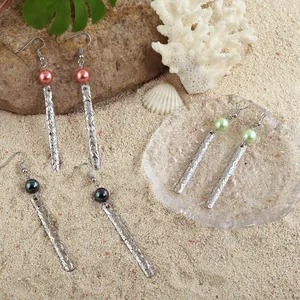 Hawaiian style silver dangle earrings with pearls and engraved metal bars on beach sand