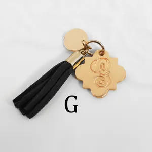 Golden flower charm with letter G engraving and black suede tassel on a keychain