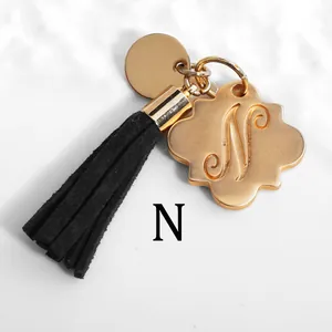 Detailed macro of golden letter N pendant with black suede tassel and metal tag