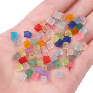 Hand holding colorful 5mm frosted sugar cube glass beads for DIY jewelry making