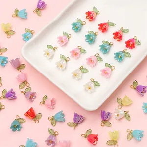 Colorful lily of the valley acrylic flower charms with gold loops on a white ceramic tray