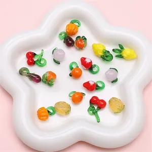 Nahaufnahme bunter Glasanhänger in Obstform in einer weißen Keramikschale