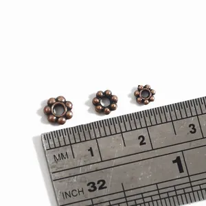 Vintage bronze plum flower spacer beads for DIY jewelry making shown with ruler
