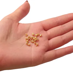 Hand mit 18K vergoldeten Quetschperlen für DIY-Schmuckherstellung mit glatter Oberfläche
