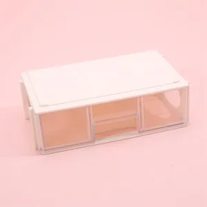 Close-up of a minimalist desktop storage box with clear plastic drawers on pink backdrop