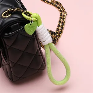 Neon green braided polyester lanyard keychain with heart charm on a black bag