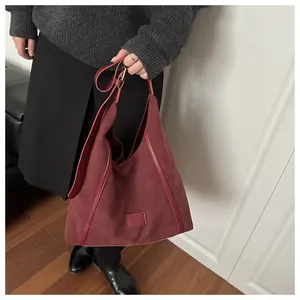 Detail of burgundy suede tote bag showing large capacity and soft texture on a shoulder