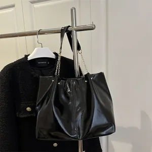 Large black glossy tote bag with chain strap and soft pleated texture for women