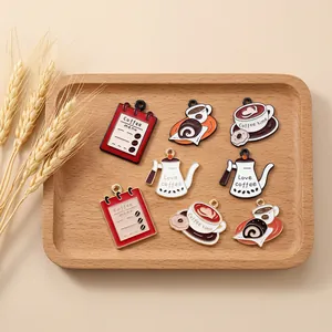 Detail of assorted vintage coffee enamel charms including menus and pots in a wooden tray