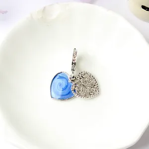 Dettaglio macro del ciondolo a doppio cuore argento con smalto blu e pavé scintillante