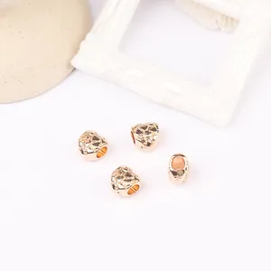 Makrofoto von roségoldenen Perlen mit Bruchstruktur und großen Löchern für DIY-Schmuck
