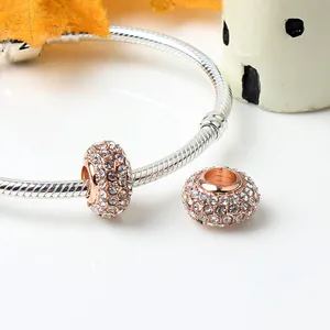 Macro view of crystal-encrusted pave spacer beads on a silver snake chain bracelet